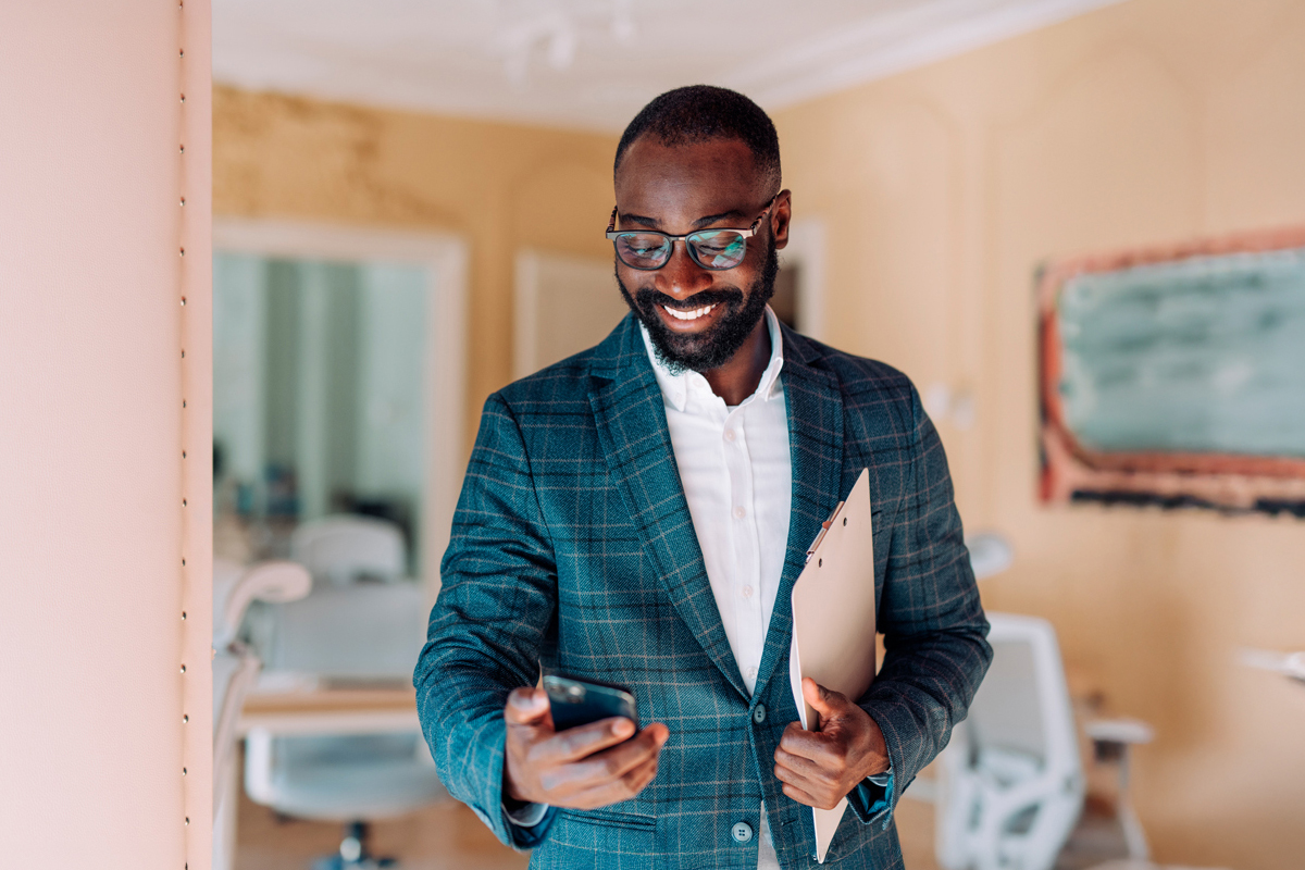 man inside of residential home in a suit looking at his phone 