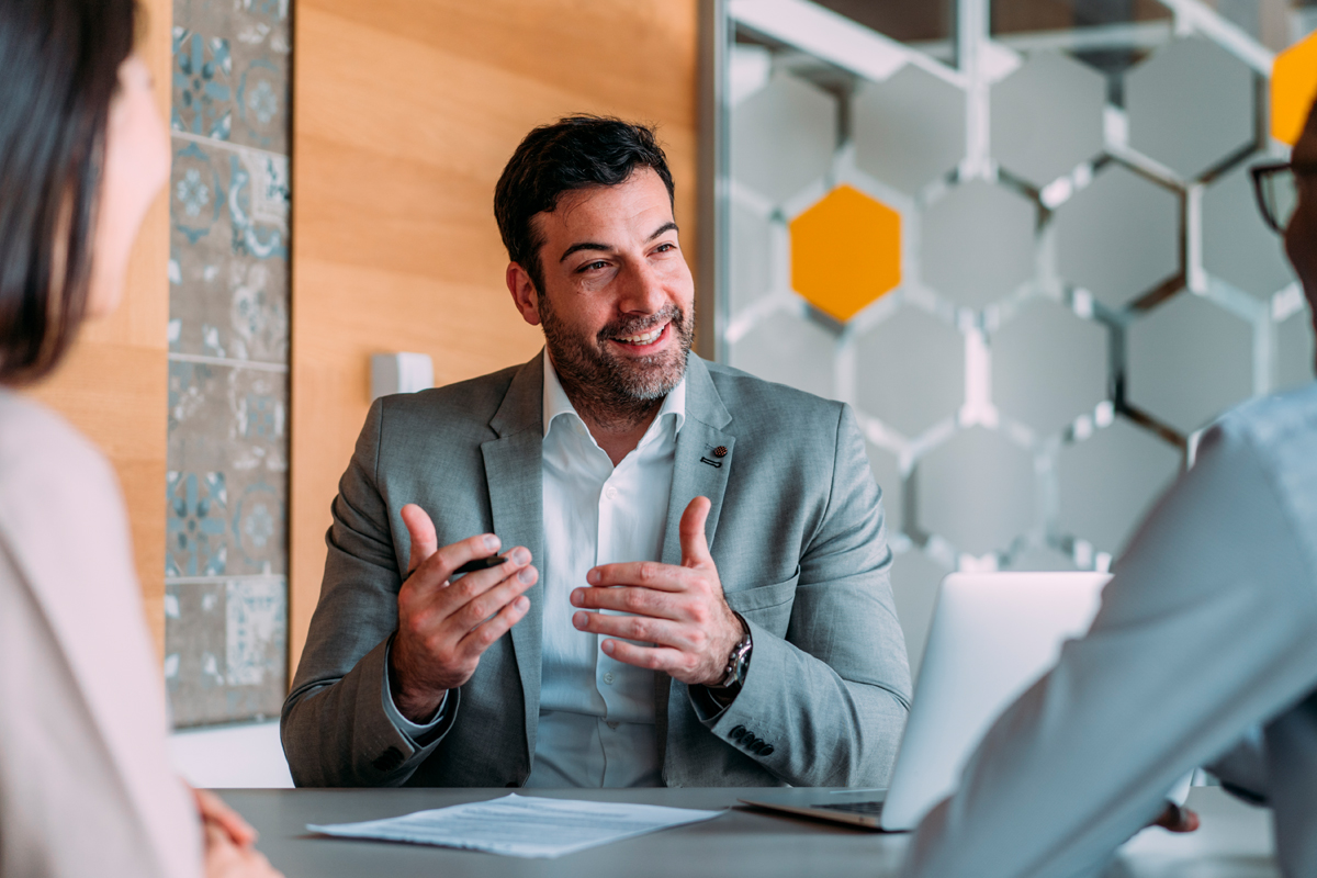 man sitting at table talking to two people 