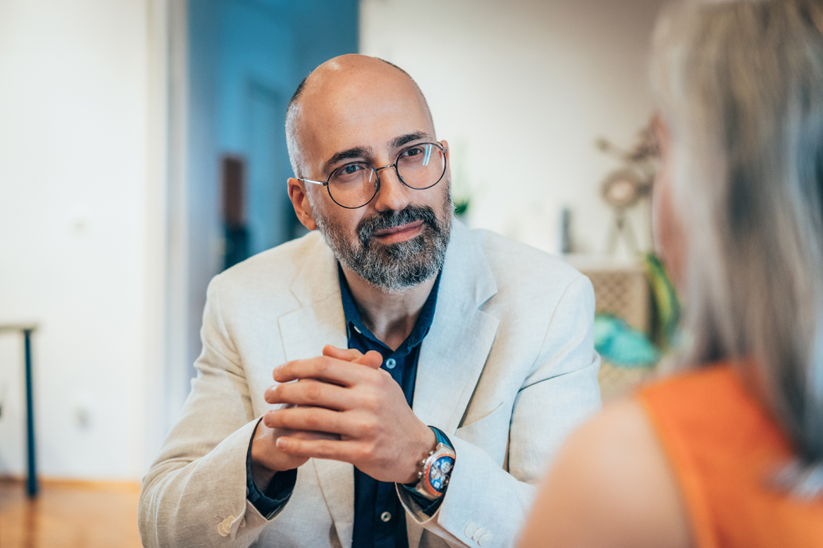 man sitting at table talking to woman 